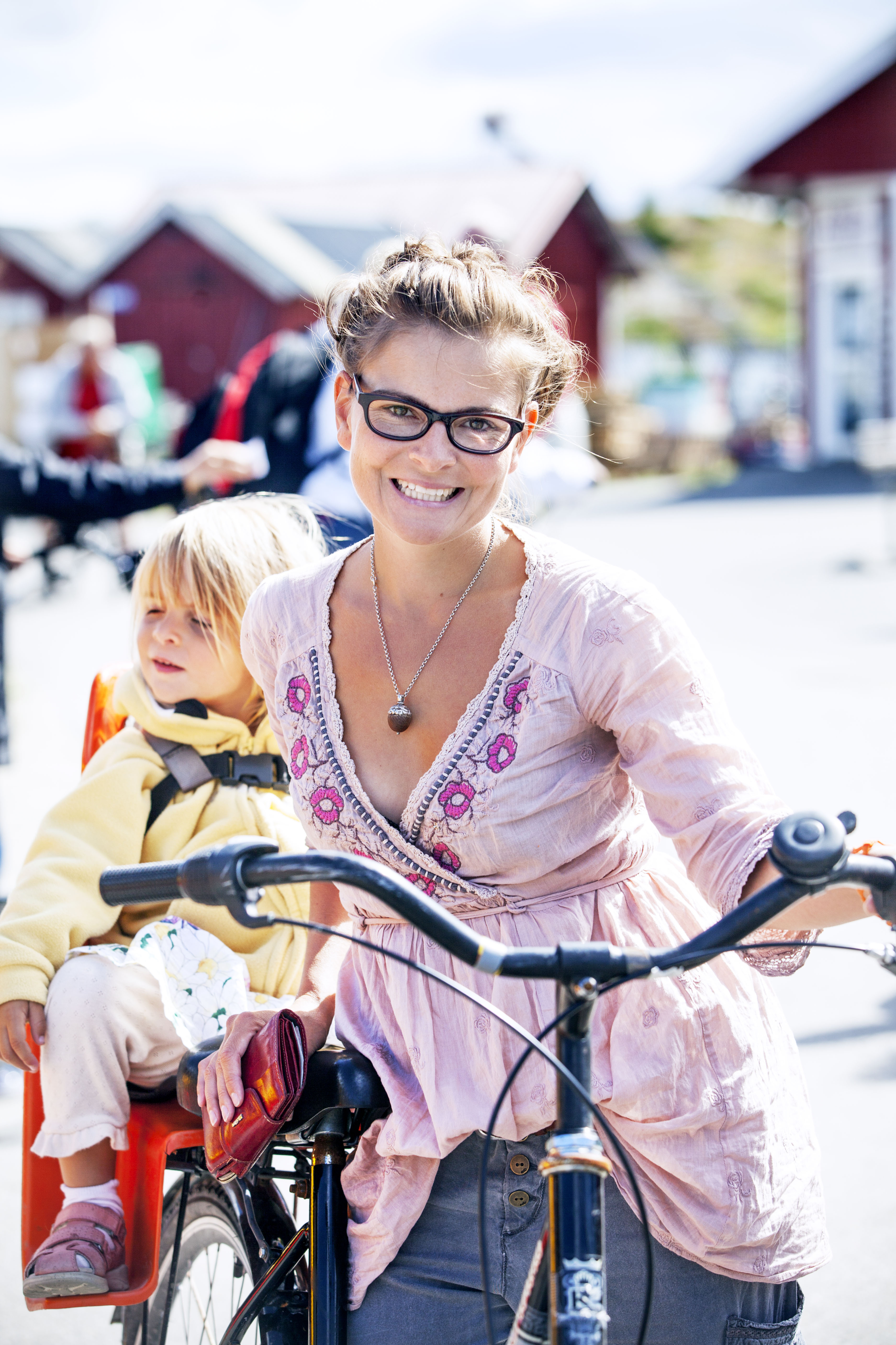 En mamma med sitt barn och mamman håler i en cykel
