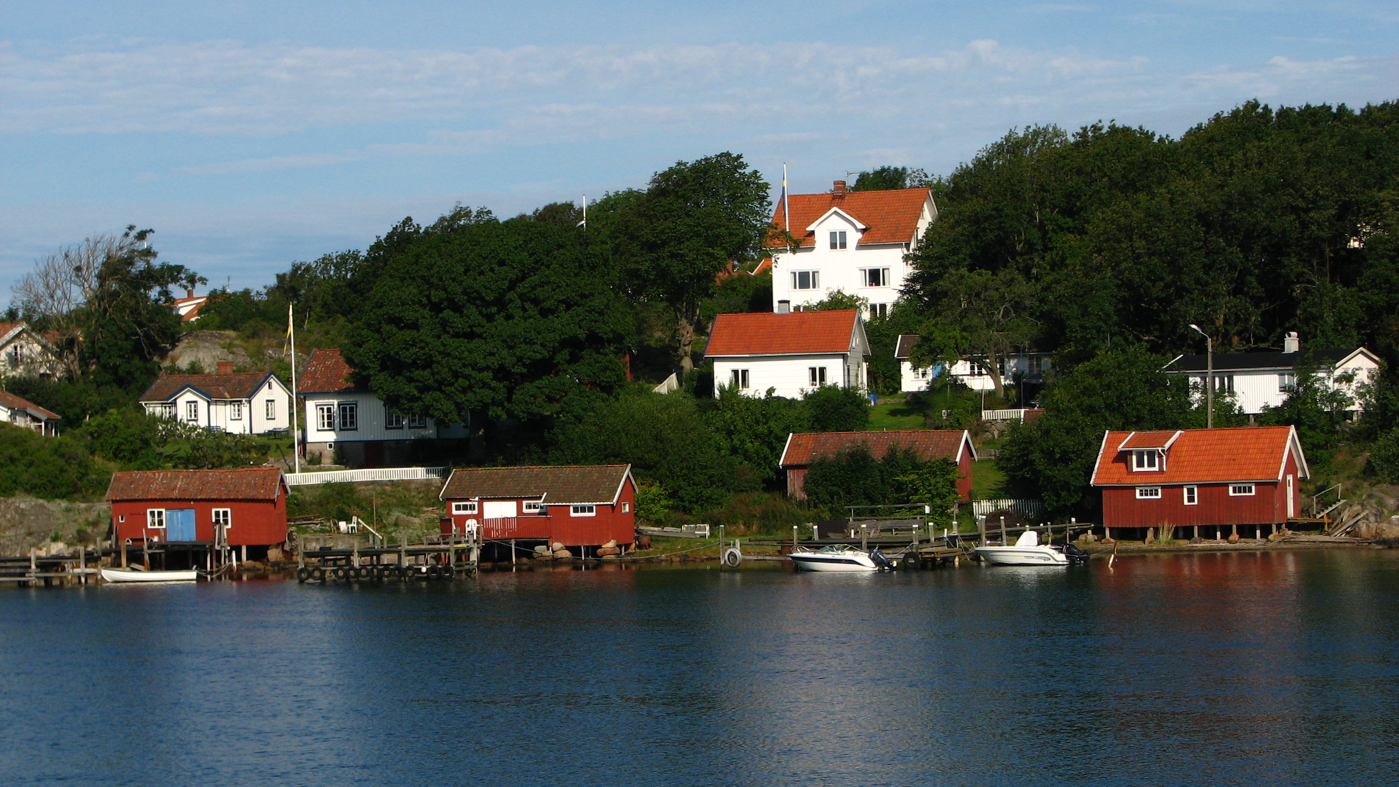 Vita sommarhus med röda sjöbodar vid havet